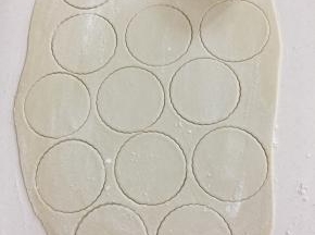 面片上撒少许面粉，用大饺子皮模具按压成小圆片。