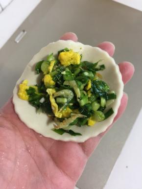 取一个面片，放入适量的鸡蛋虾皮韭菜馅儿。