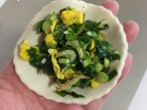 取一个面片，放入适量的鸡蛋虾皮韭菜馅儿。