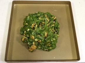 把雪花酥团倒入不粘烤盘内，用双手不停往外翻，直到饼干和坚果料都被千丝万缕的糖包裹住。