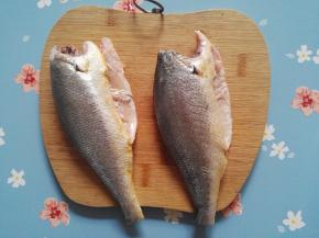 2、小黄鱼，去鳞去鱼头去内脏，并清洗干净，用厨房用纸将鱼身上的水分吸干，用刀将鱼身切成1.5厘米左右的小段。