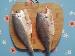 2、小黄鱼，去鳞去鱼头去内脏，并清洗干净，用厨房用纸将鱼身上的水分吸干，用刀将鱼身切成1.5厘米左右的小段。