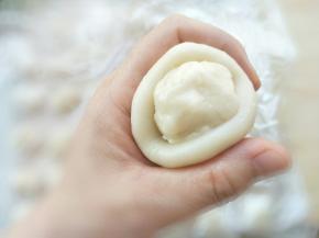 取一个油皮包入油酥。用手的虎口位置，慢慢把油酥塞进去，收口捏紧。