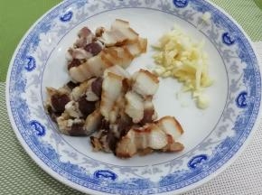 腊肉焯水，然后切成薄片，蒜切成粒