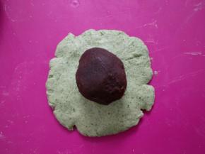 取一份艾草糯米团按扁，包入一份豆沙馅 。