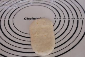 松弛好的面团再次排气，擀成长舌形