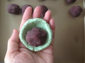 豆沙馅分成14个，每个20克，搓圆。艾叶粉团分成每个50克，搓圆后用拇指压成碗状，放入豆沙馅