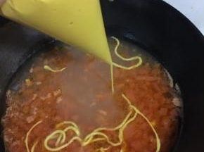 裱花袋剪一个小口，把面糊均匀的挤到锅里。记得要开大火哦，边挤边煮，面条入锅就会快速凝固，如果面糊调的太稀或者火小了就变成面疙瘩啦。