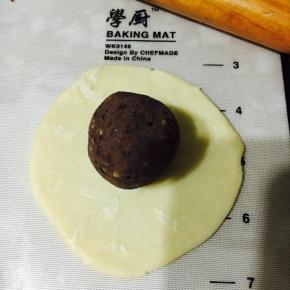 放入馅料，以推的手法将面皮推至收口处，收紧收口！这样做出来的蛋黄酥底层就不会太厚，影响口感！