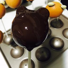 把黑巧克力液淋满整个棒棒糖。「棒棒糖头朝下垂直一会，可以过滤下多余的巧克力液，使其表面更光滑，不会从纸棒流下。」