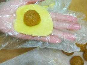 取一个皮用掌心按扁，再按大些，厚薄要均匀，以刚好包下一个馅略大些为宜。