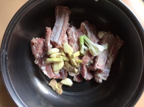 将排骨放入盆中，加入姜、蒜白、蒜瓣
