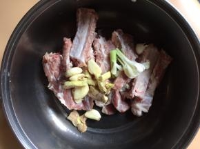 将排骨放入盆中，加入姜、蒜白、蒜瓣
