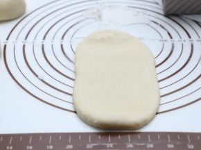 取出发酵好的面团进行排气，分隔成两个吐司盒用量（450g+水立方吐司盒一个用量）排气后擀至长舌状后从一端卷至另一端。