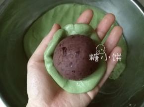 取一团分好的糯米皮压扁，中间包入红豆馅