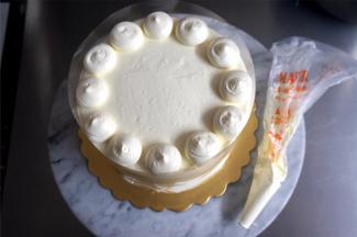 将剩余的淡奶油装入裱花袋，减去一个约1厘米长的开口，将奶油挤到蛋糕表面边缘，如图。