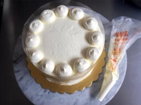 将剩余的淡奶油装入裱花袋，减去一个约1厘米长的开口，将奶油挤到蛋糕表面边缘，如图。