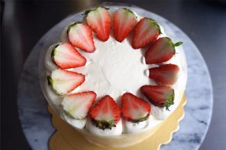 草莓洗净后对半切开，尖朝内，切面朝上，放在奶油球上。