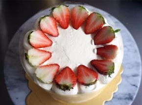 草莓洗净后对半切开，尖朝内，切面朝上，放在奶油球上。