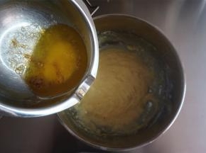 从烤箱取出融化的黄油加入到面糊中（黄油表面有点焦化，如有黑点，可以先过滤后加入），拌至黄油完全融合。