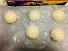 把面团分割成小面团。每个面团大概100克左右。将面团滚圆，盖上保鲜膜发酵30分钟。