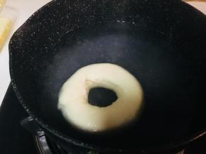 取一个锅，放入水和糖。煮沸。小火保持温度，但不要冒大泡泡。将面圈放入锅中，每面30到40秒。取出沥干多余水分。