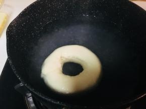 取一个锅，放入水和糖。煮沸。小火保持温度，但不要冒大泡泡。将面圈放入锅中，每面30到40秒。取出沥干多余水分。