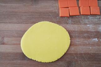 再分别把每份翻糖膏擀开，用小刀划出均匀的小正方形翻糖片（翻糖片的尺寸大小，要按照蛋糕体的尺寸计算好，即3块翻糖片边长总和+缝隙尺寸=蛋糕体边长）