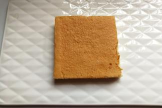 先取一块蛋糕片在底部抹上适量奶油，使蛋糕片固定在盘子中间