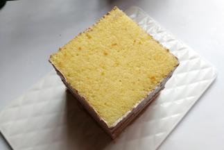依次叠加六层蛋糕片，要使蛋糕体的高度和蛋糕体的边长一样，最后再把四周多余的奶油用抹刀刮刀稍微带平整，再放入冰箱先冷藏一下