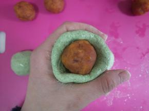 取一面团整成窝窝状，放入一个馅料，慢慢往上推，收口朝下，滚圆。