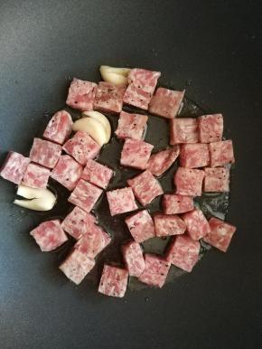 大蒜炒出香味时，加入牛仔粒，大火翻炒。