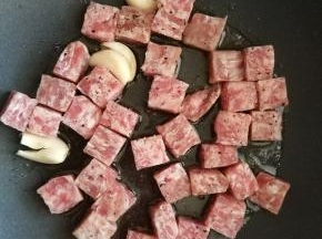 大蒜炒出香味时，加入牛仔粒，大火翻炒。