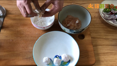 码味后，将鸡片捋直，少量粘上淀粉，然后裹成球状，再放入淀粉中将鸡球均匀的裹上淀粉，并用手将鸡球捏紧，避免下一个操作时鸡球散开