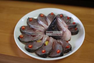 放上鱼头和鱼尾，从缝里插入姜片，摆上辣椒段