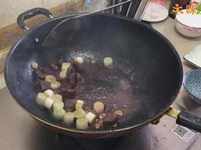 锅重新烧热，加入三分之一汤勺的油，然后放入切好的姜、蒜、洋葱，炒出香味后，再加入大葱段炒出香味，加入适量红酒，再放入煎好的牛肉块翻炒