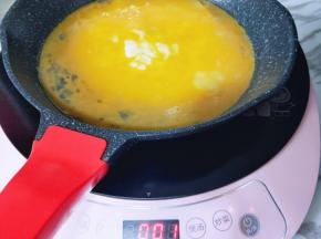 油温6成时将打散的蛋液倒入平底锅中。