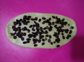 取一个面团擀开成舌状，铺满蜜红豆。