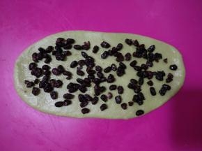 取一个面团擀开成舌状，铺满蜜红豆。