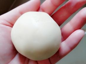 月饼皮包住豆馅，翻过来慢慢收口。