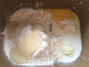 先准备好全部材料，黄油跟马苏里拉奶酪室温软化，面包桶内加入高筋面粉、细砂糖、奶粉、炼乳、全蛋液、酵母跟牛奶