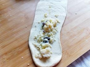 取一块面团，擀成长舌状，放上做好的椰蓉馅，卷起来。