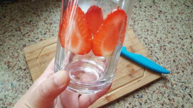 把切好的草莓片，沿着杯子绕一圈贴在杯壁上做装饰。