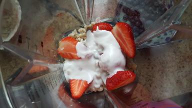 在破壁机的搅拌杯中放入谷物和切好的草莓，加适量的椰浆。（如喜甜者可以适量的加些蜂蜜或炼乳）