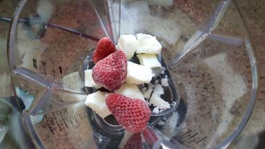 在破壁机机的搅拌杯中放入冻硬的酸奶和梆梆硬的草莓，草莓我都是整颗放在里面打的，不过建议大家可以切开，那样粉碎的更快，效果都是一样的。