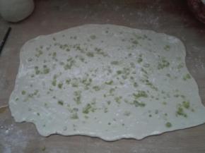 4.发酵好的面团排气，等分两份，取一个剂子擀成大长方形薄片，刷一层，撒葱花，盐适量