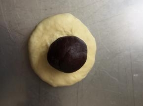 取一个面团，压扁，放一个豆沙馅儿