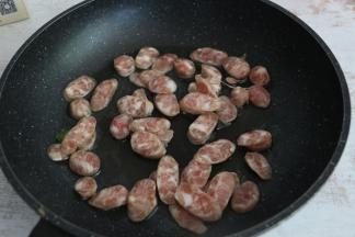 平底锅内倒入适量食用油，放入香肠片翻炒。
