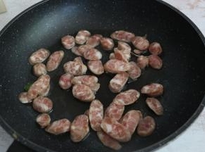 平底锅内倒入适量食用油，放入香肠片翻炒。