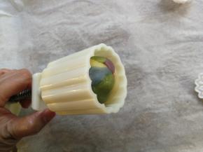 饼模的花片安装好之后，将整理好的彩色椭圆形绿豆糕以顶部面朝花片的方向放进饼模